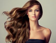 Szép, fiatal nő, hullámos, hosszú, barna hajjal egy budapesti fodrász hajgyógyász sminkes szalonban