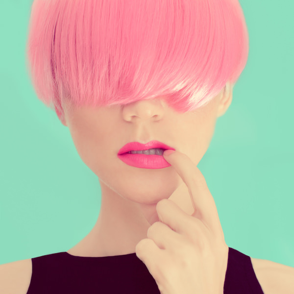 Fiatal nő rózsaszín hajjal és rúzzsal, a szemét takaró frufruval egy budapesti fodrász hajgyógyász sminkes szalonban